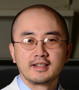 headshot of an asian man with glasses and a labcoat