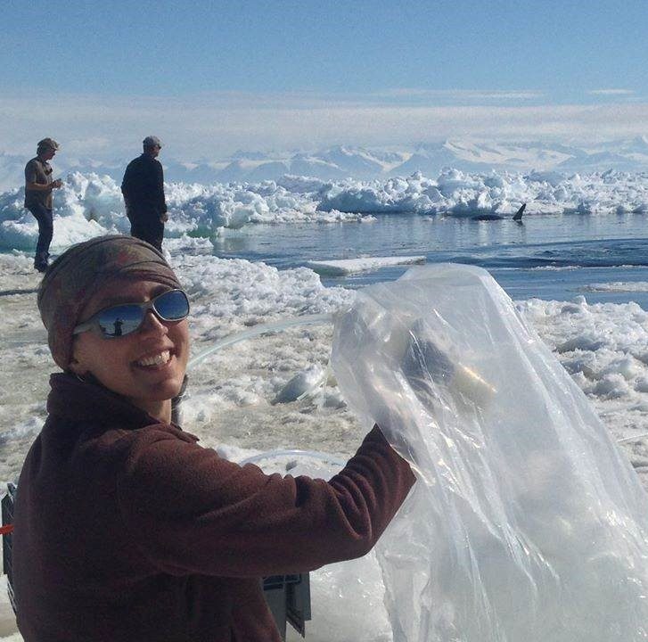 a woman holding a plastic bag on a glacier, with two people in the background