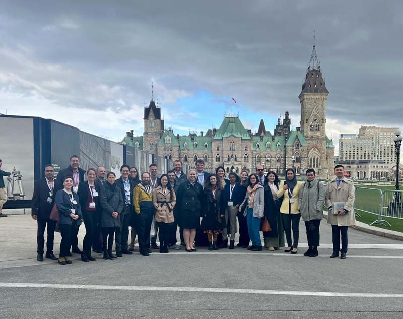 Large group of CSPC attendees posing for the camera in from of the parliament building