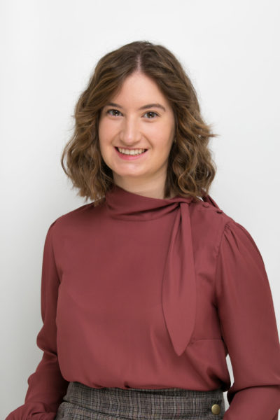 A headshot of a white woman with short brown hair and a red blouse.