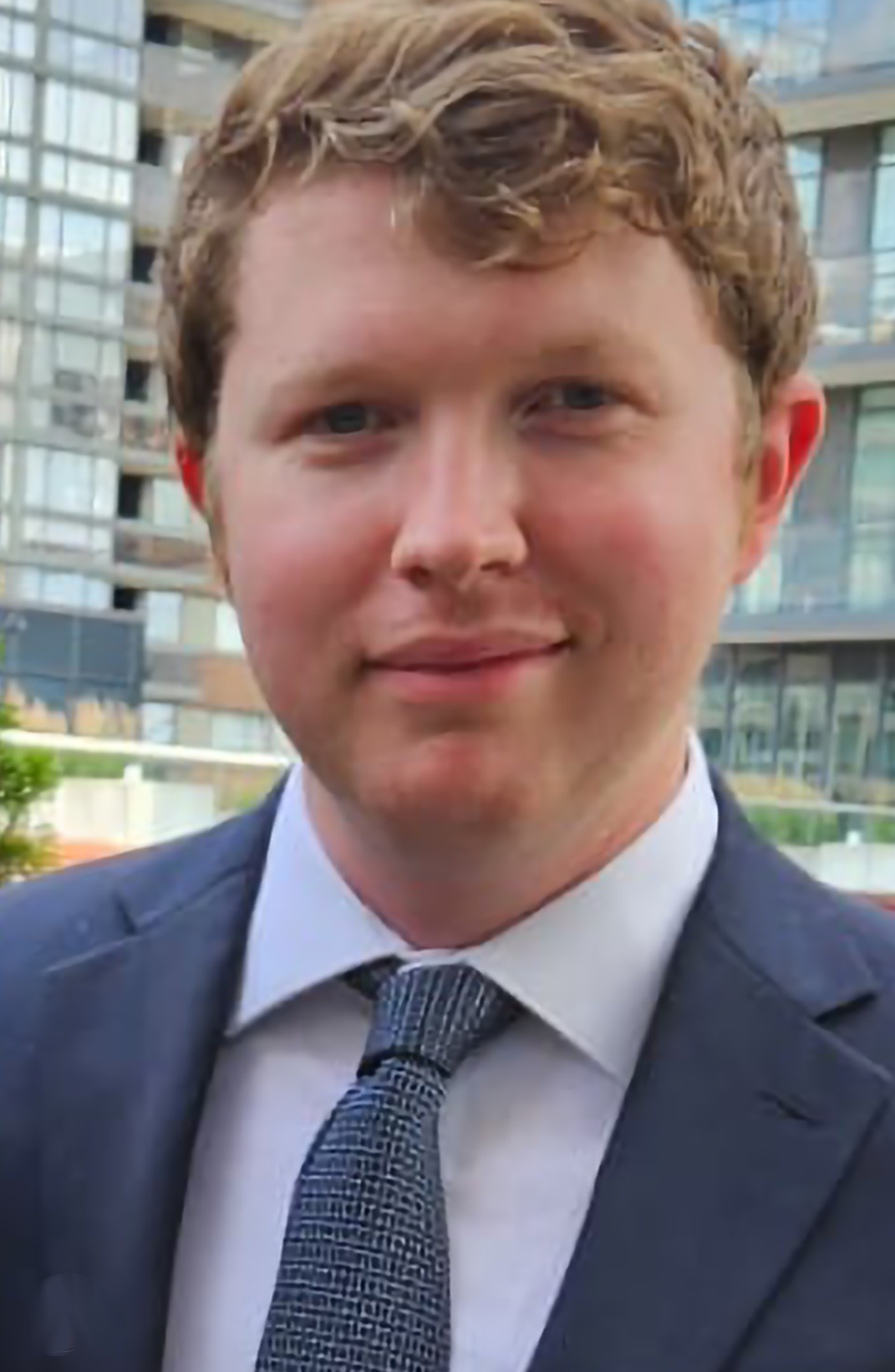 headshot of a white man in a blue suit.