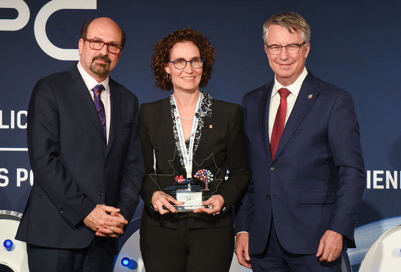 Dr. Catherine Beaudry holding award with two award presenters