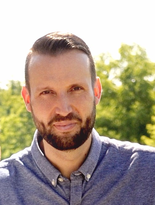 Photo d'un homme blanc avec une barbe et une chemise bleue.