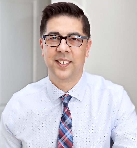 Photo of a middle eastern man in glasses and a white shirt and tie.