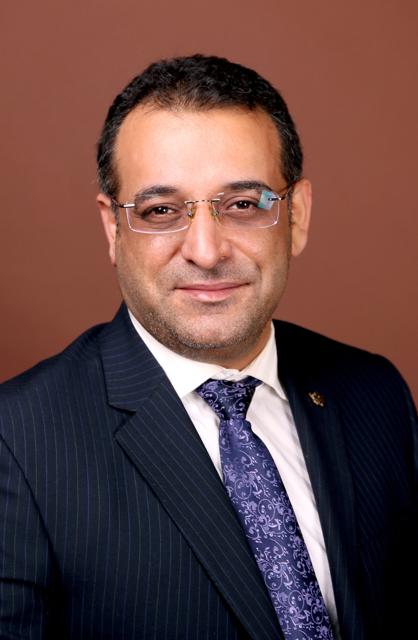Headshot of an arab man in glasses and a suit
